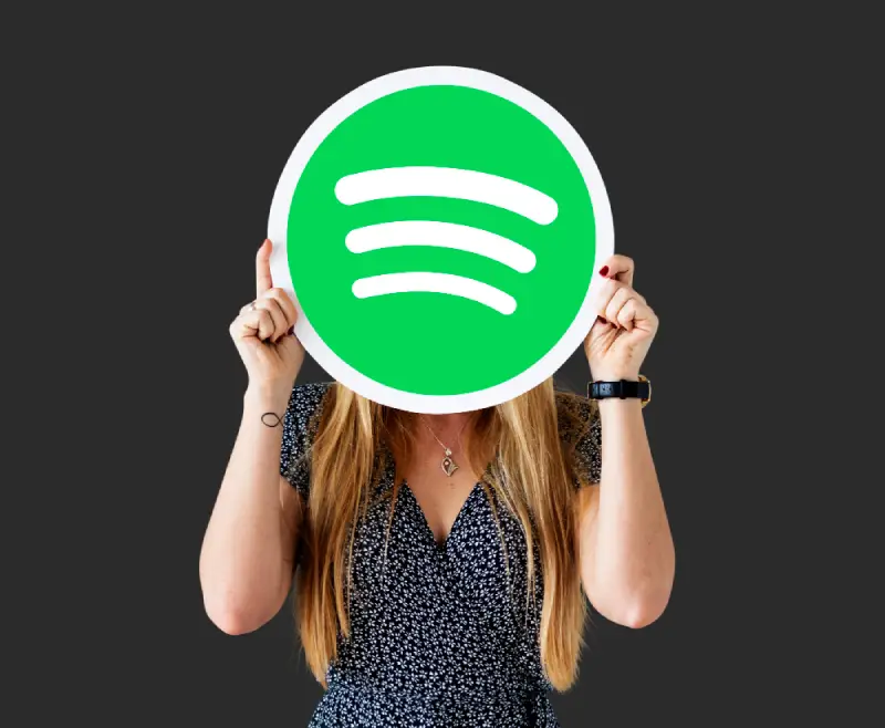 A Woman holding up a spotify icon
